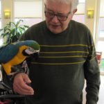 Ein Pflegeheim-Bewohner trägt einen Papageien auf dem Arm.